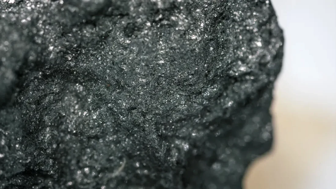 Close-up of a dark graphite specimen with a layered surface
